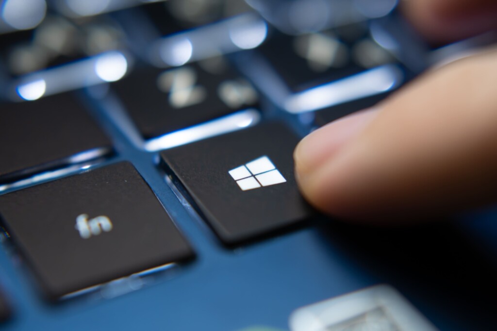 Close-up of a finger pressing the Windows key on a laptop keyboard