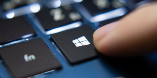 Close-up of a finger pressing the Windows key on a laptop keyboard