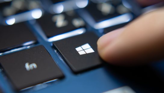 Close-up of a finger pressing the Windows key on a laptop keyboard