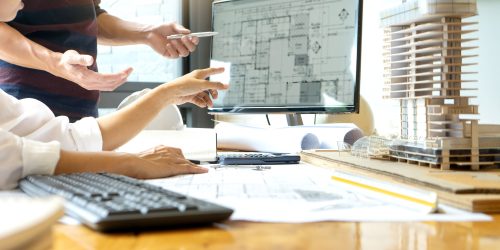 Architects reviewing digital blueprints on a computer screen with a building model, representing reliable IT services for architects in Central Ontario