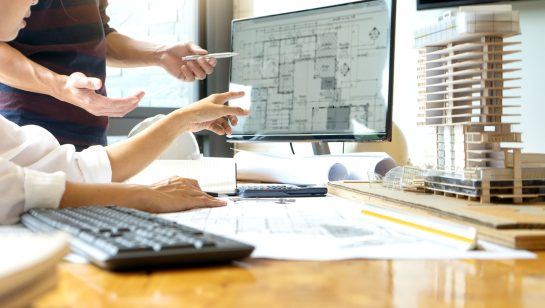 Architects reviewing digital blueprints on a computer screen with a building model, representing reliable IT services for architects in Central Ontario