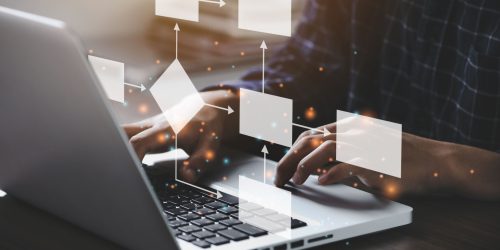 Person typing on laptop with digital flowchart graphics overlay