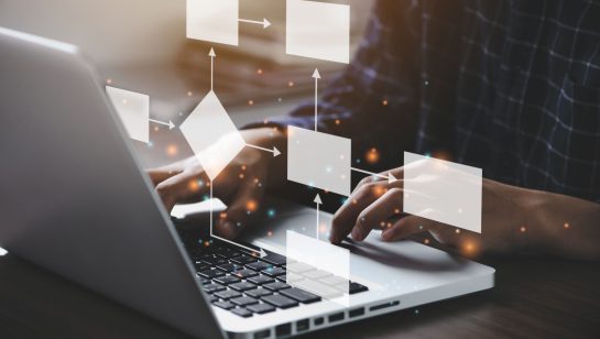 Person typing on laptop with digital flowchart graphics overlay