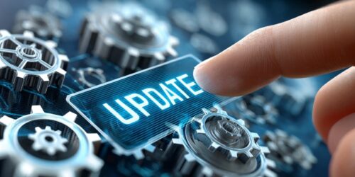 Finger pressing a virtual ‘Update’ button over digital gears, symbolizing essential technology updates and emerging tech trends for businesses.