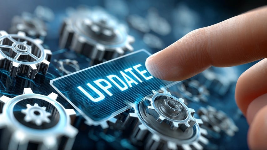Finger pressing a virtual ‘Update’ button over digital gears, symbolizing essential technology updates and emerging tech trends for businesses.