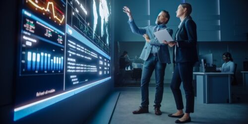 Business leaders reviewing analytics and performance data on a large digital dashboard, representing technology strategy and insights for future success