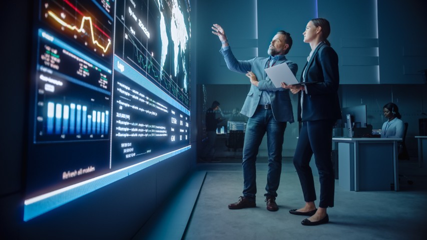 Business leaders reviewing analytics and performance data on a large digital dashboard, representing technology strategy and insights for future success