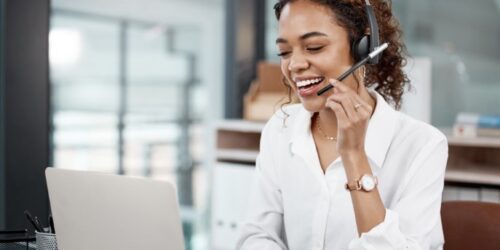 Customer support professional wearing a headset and working on a laptop in an office environment