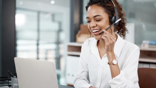Customer support professional wearing a headset and working on a laptop in an office environment