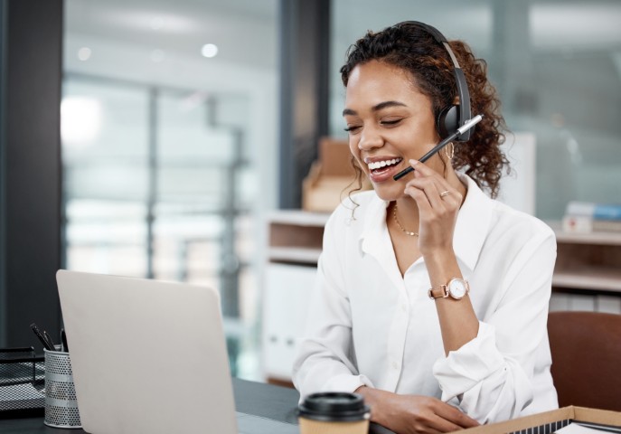 Customer support professional wearing a headset and working on a laptop in an office environment