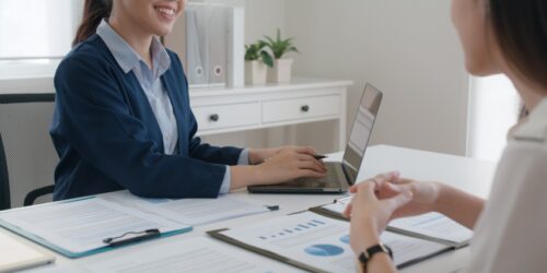 Business professional meeting with a client and reviewing documents on a laptop, representing the process of hiring IT consultants