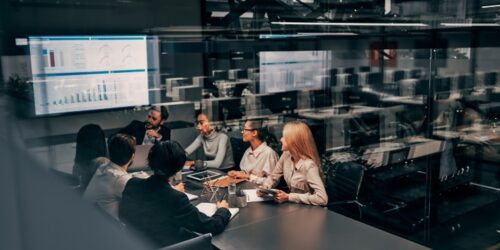 Business team collaborating in a modern conference room with data dashboards displayed on a large screen