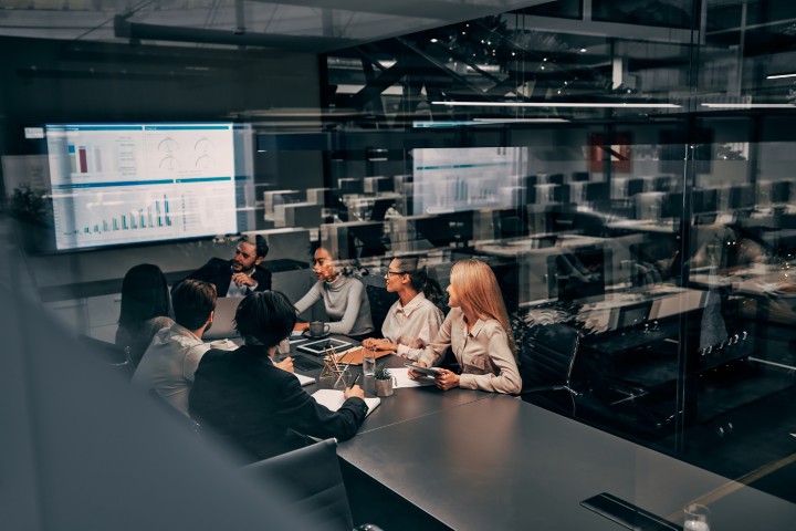 Business team collaborating in a modern conference room with data dashboards displayed on a large screen