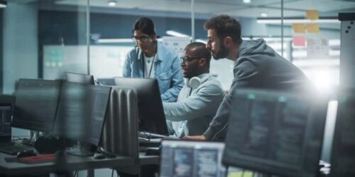 Diverse Group of Professionals Meeting in Modern Office: Brainstorming IT Programmers Use Computer Together, Talk Strategy, Discuss Planning. Software Engineers Develop Inspirational App Program