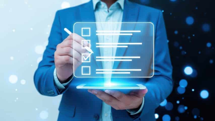 Person typing on a laptop with digital document and checklist icons, representing managed network security services in Central Ontario