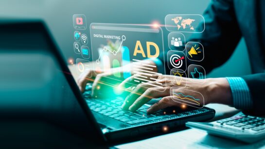 A panoramic, wide-angle shot of a person typing on a laptop, surrounded by glowing neon holographic icons representing digital marketing and business analytics. A central digital window displays a bar chart, a line graph, and the bold text 