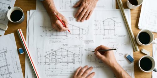 Architects Hands Working on Building Blueprints and Architectural Drawings