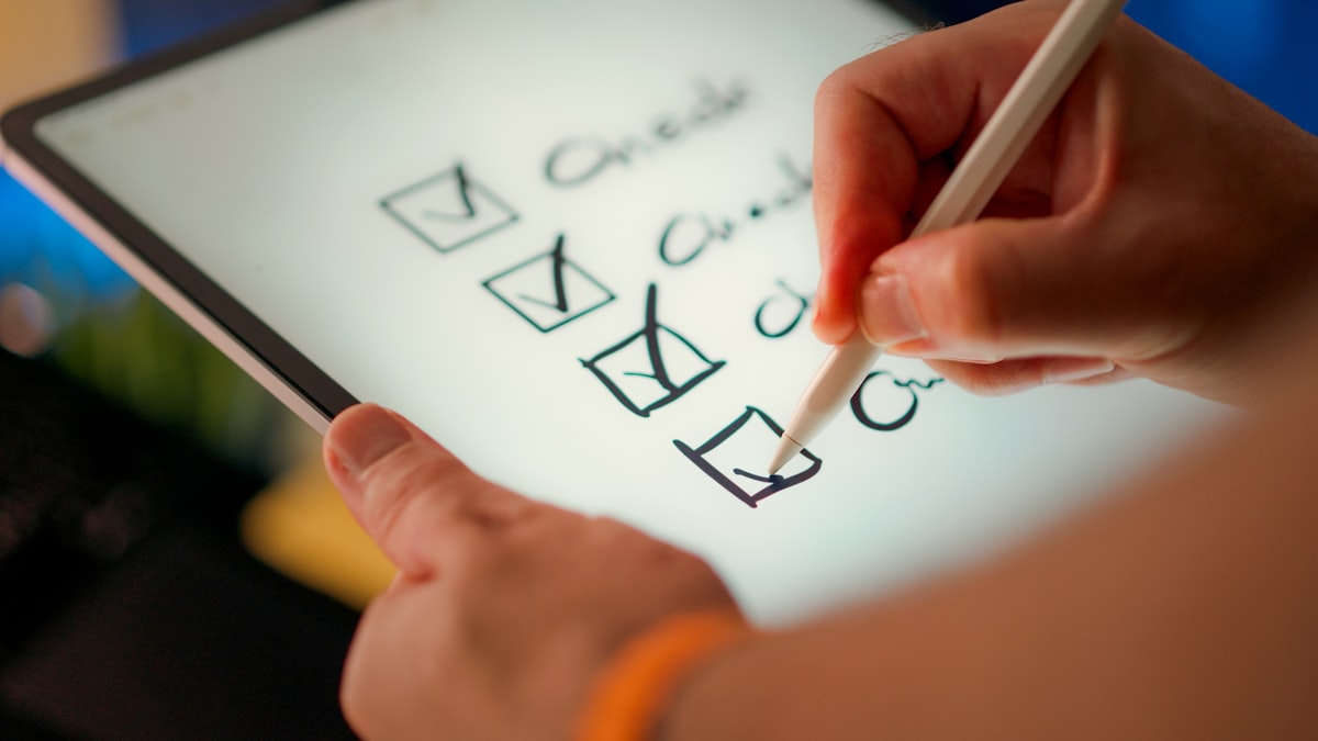 Hand checking off items on a digital checklist representing vendor and insurer documentation
