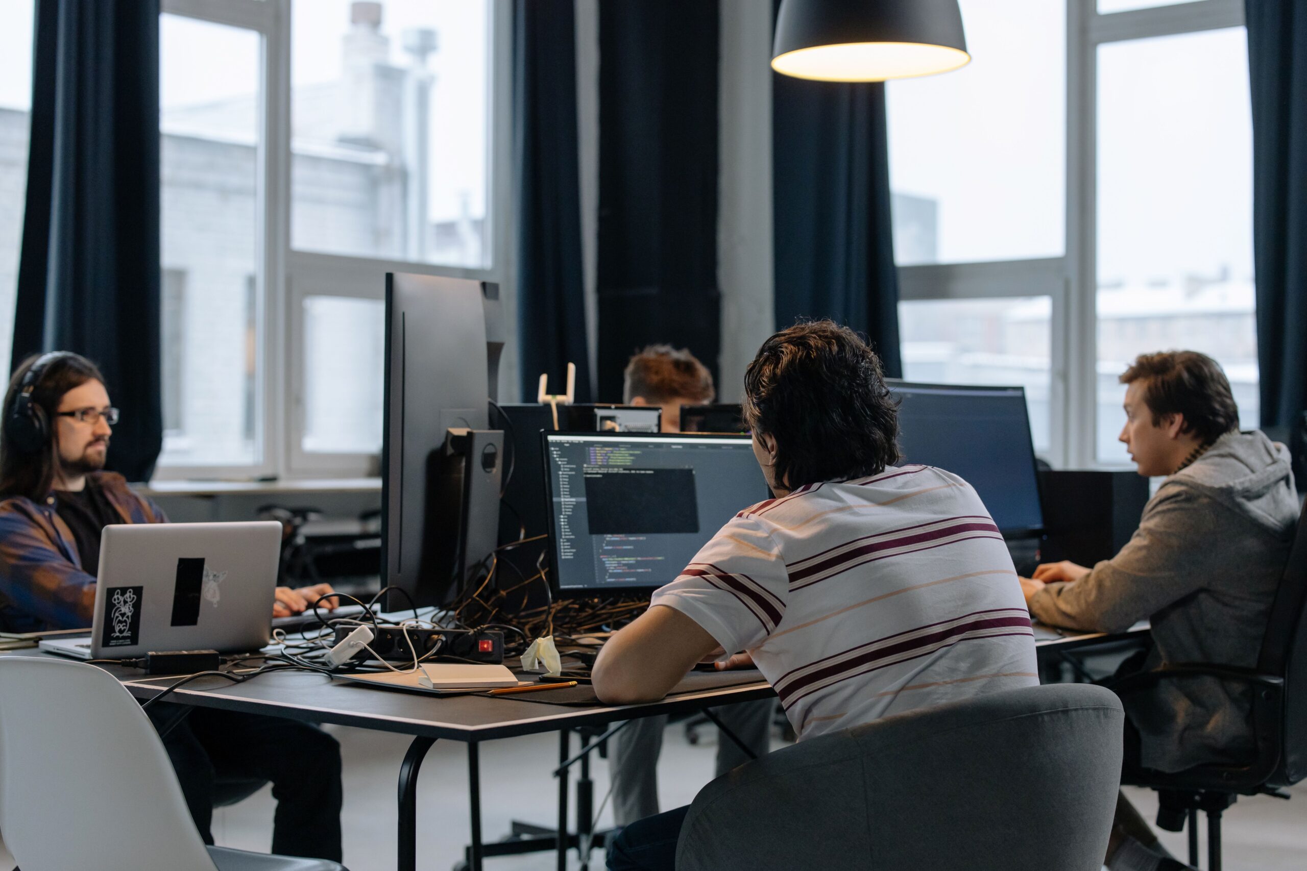 Team of IT professionals working together on computers in a modern tech office
