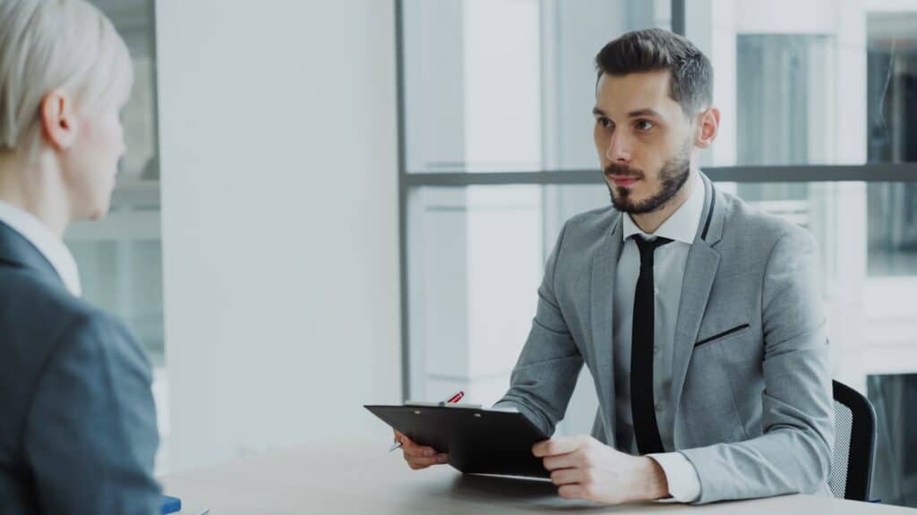 Two professionals in a business meeting reviewing a clipboard, representing the evaluation process before choosing an IT company