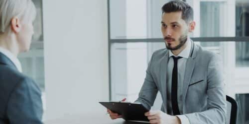 Two professionals in a business meeting reviewing a clipboard, representing the evaluation process before choosing an IT company