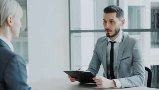 Two professionals in a business meeting reviewing a clipboard, representing the evaluation process before choosing an IT company