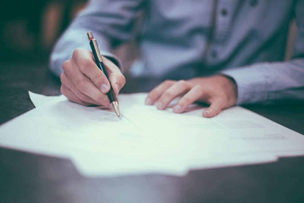 Man writing on paper, representing signing an IT support contract