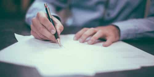 Man writing on paper, representing signing an IT support contract