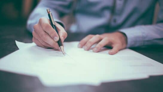 Man writing on paper, representing signing an IT support contract