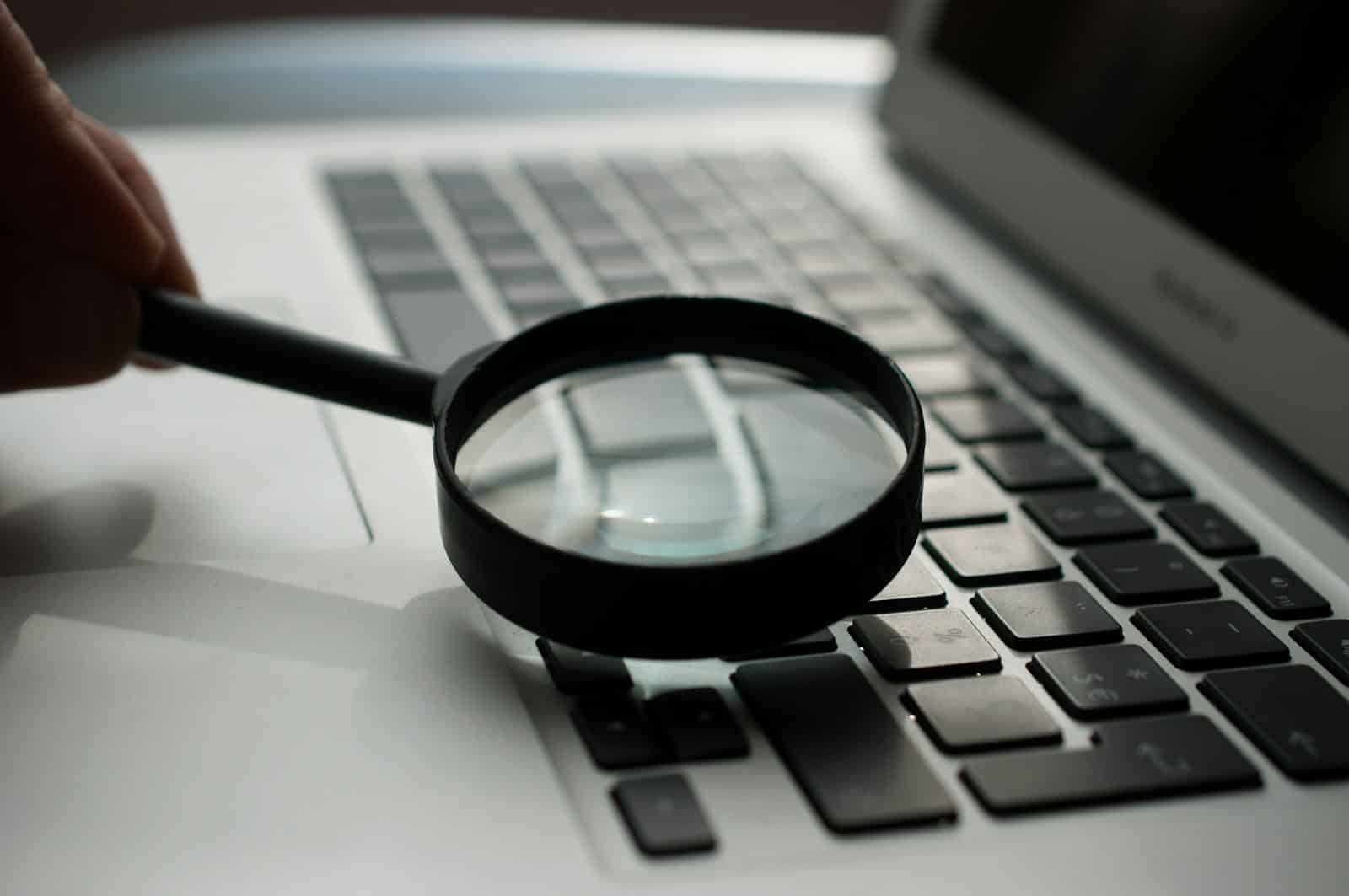 Magnifying glass beside a laptop, representing closely examining the difference between response time and resolution time