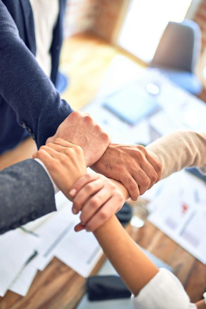 Team members gripping wrists in a unity gesture, representing a partner seeing and engaging with the full business