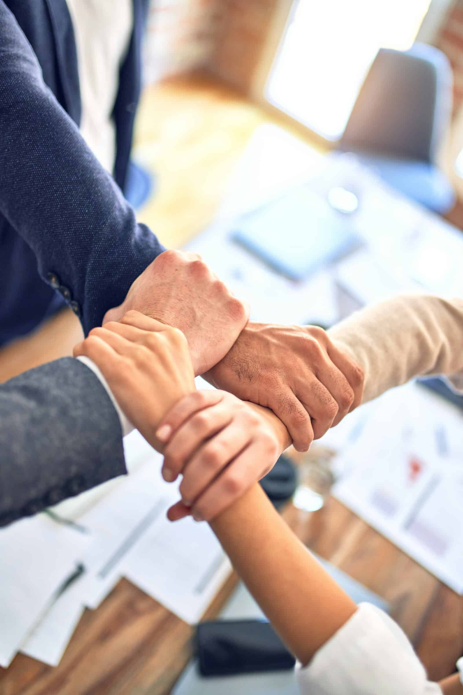 Team members gripping wrists in a unity gesture, representing a partner seeing and engaging with the full business