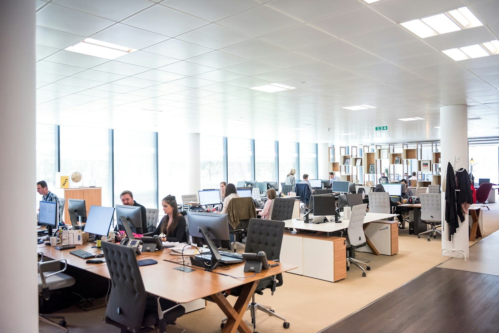 People working at desks in an open office, representing reactive ticket-based IT support