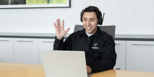 IT helpdesk technician wearing a headset providing remote support at a laptop