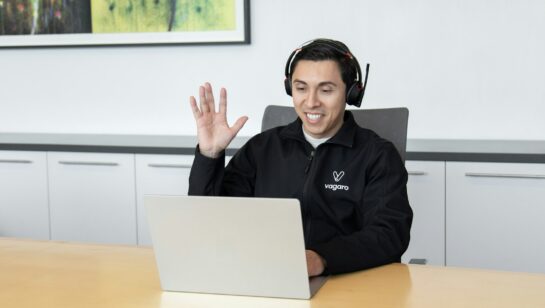 IT helpdesk technician wearing a headset providing remote support at a laptop