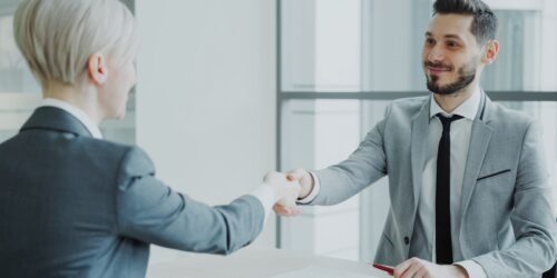 Two business professionals shaking hands, representing the start of a managed IT onboarding relationship