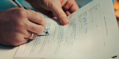 Close-up of hands signing a business services contract with a pen