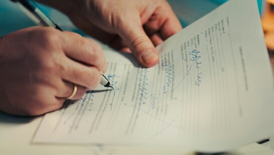 Close-up of hands signing a business services contract with a pen