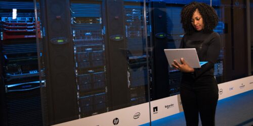 IT technician standing beside blue-lit server racks, representing the server rightsizing project for the painting contractor case study