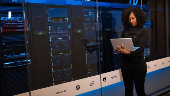 IT technician standing beside blue-lit server racks, representing the server rightsizing project for the painting contractor case study