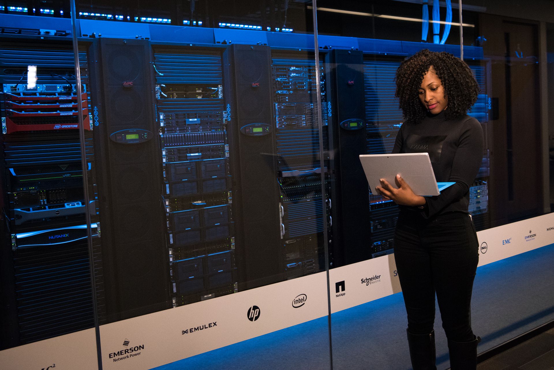 IT technician standing beside blue-lit server racks, representing the server rightsizing project for the painting contractor case study