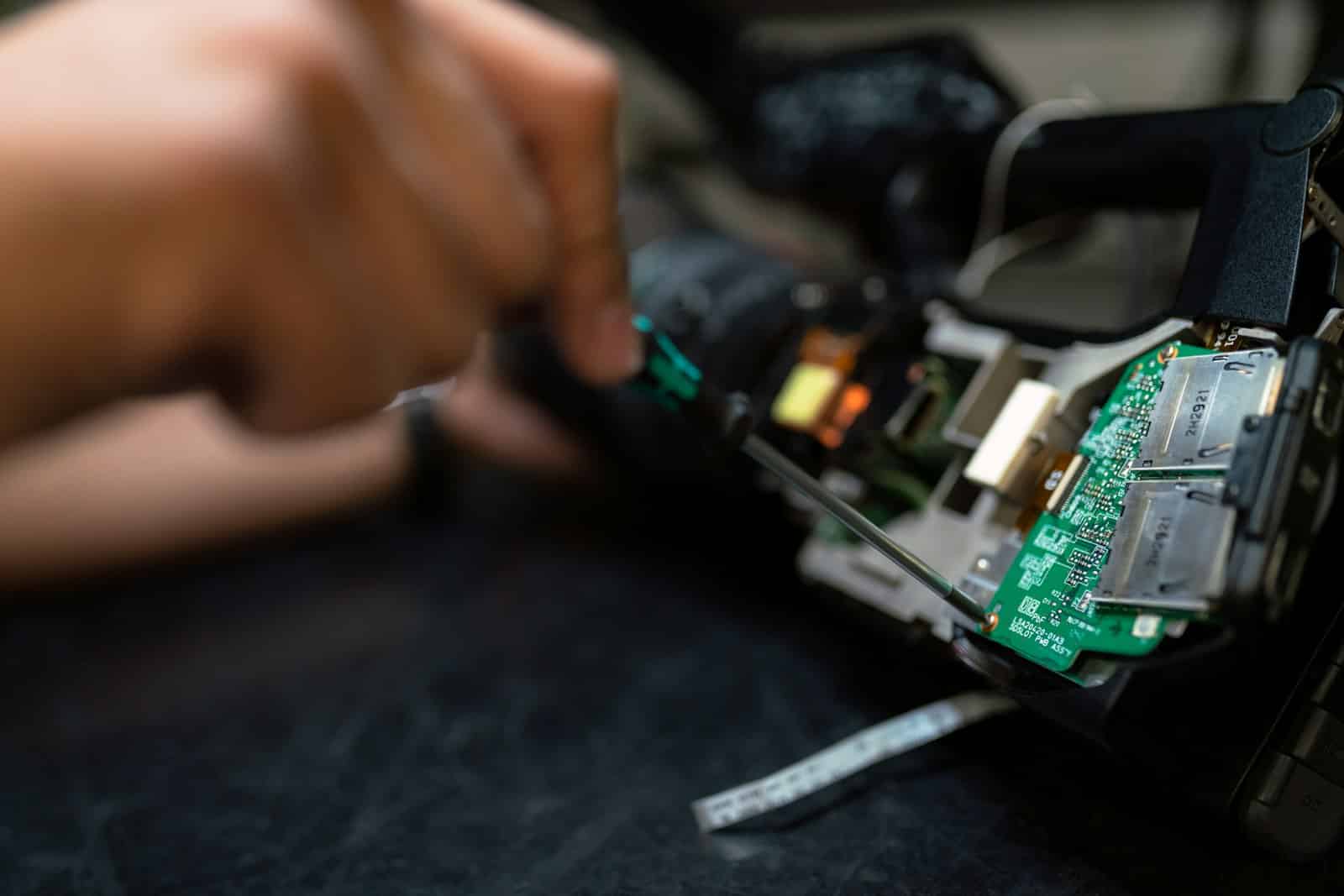 Technician physically handling a circuit board, representing hardware work that requires an on-site visit