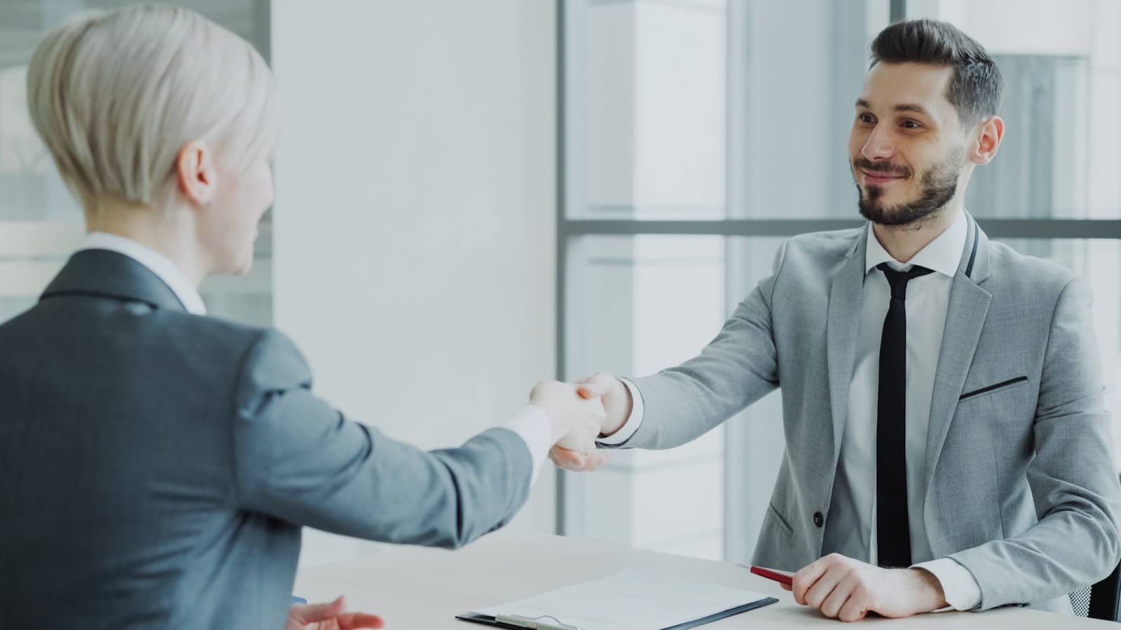 Two business professionals shaking hands, representing choosing between remote-only and full-service IT coverage