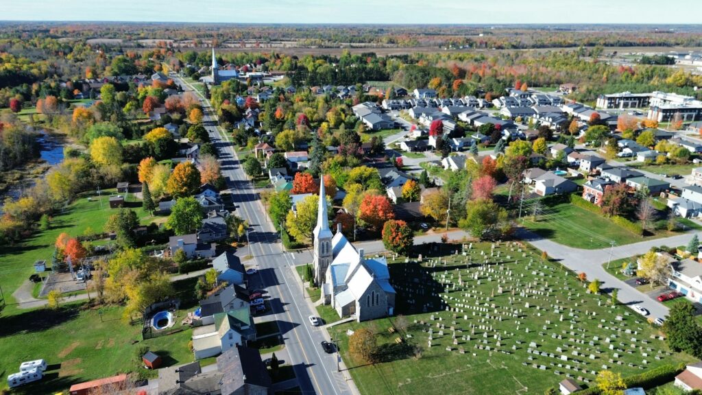 Aerial view of a small Ontario town surrounded by autumn foliage, representing the towns and townships ACT360 serves across Simcoe County