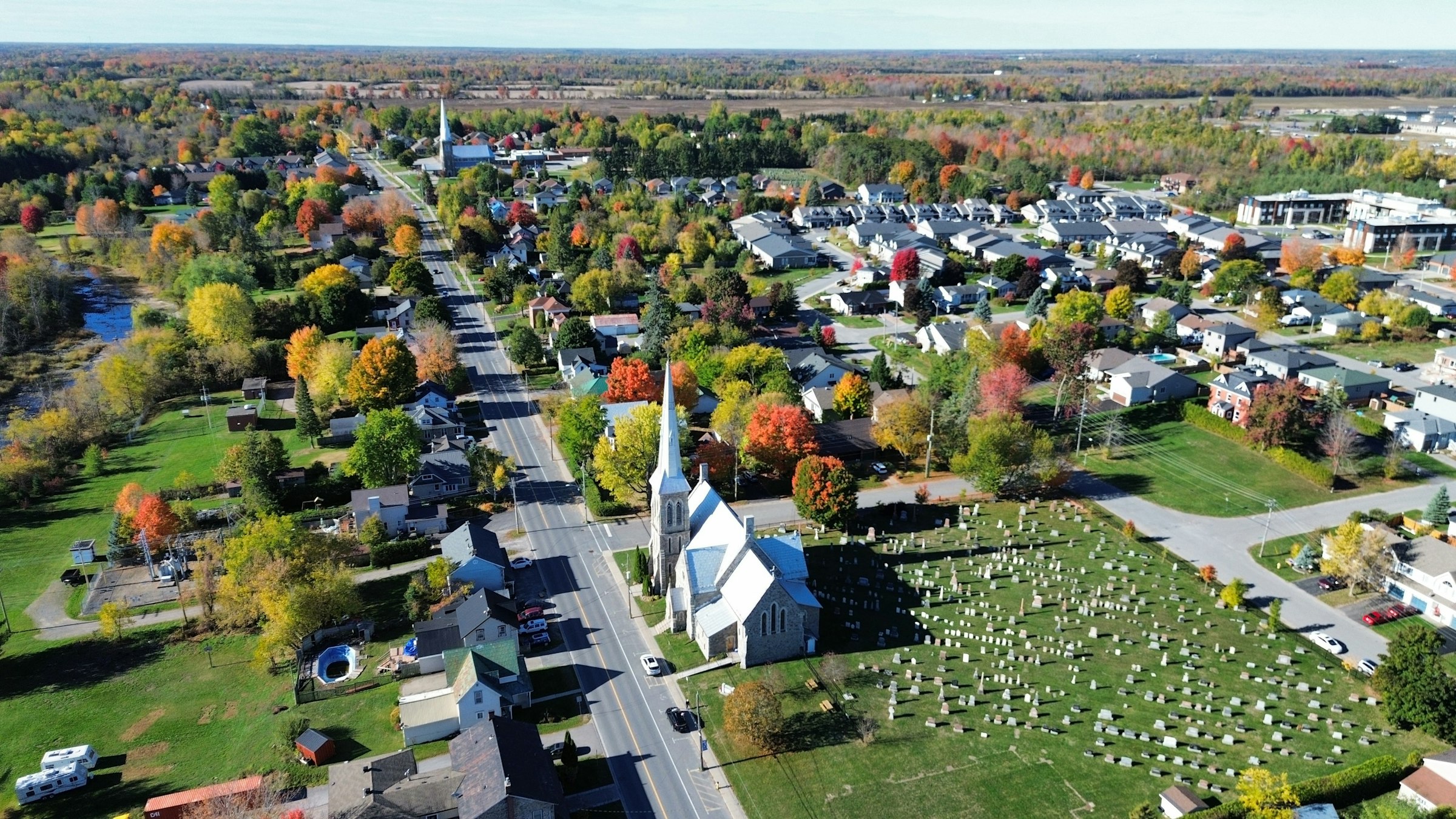Aerial view of a small Ontario town surrounded by autumn foliage, representing the towns and townships ACT360 serves across Simcoe County