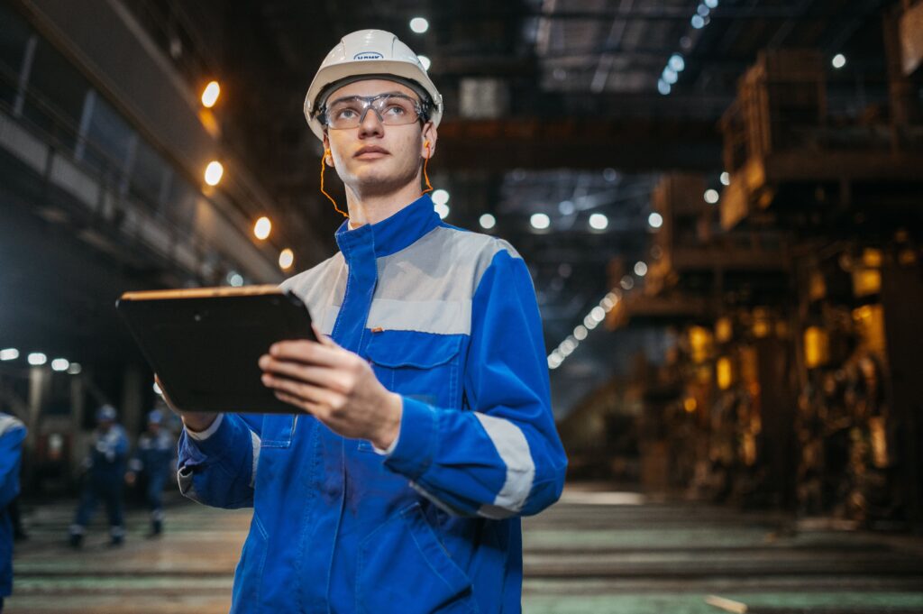 Manufacturing engineer using a tablet on the shop floor to track AI-driven production data and ROI
