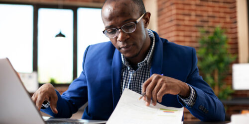 An analyst reviewing a checklist on a clipboard while working on a laptop, representing the planning process for a cloud migration