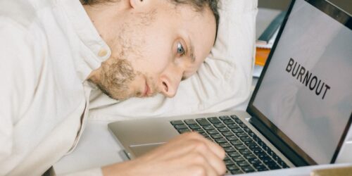Exhausted business owner resting head on desk beside a laptop, representing the frustration of being underserved by an outgrown IT provider