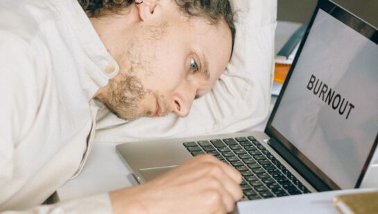Exhausted business owner resting head on desk beside a laptop, representing the frustration of being underserved by an outgrown IT provider