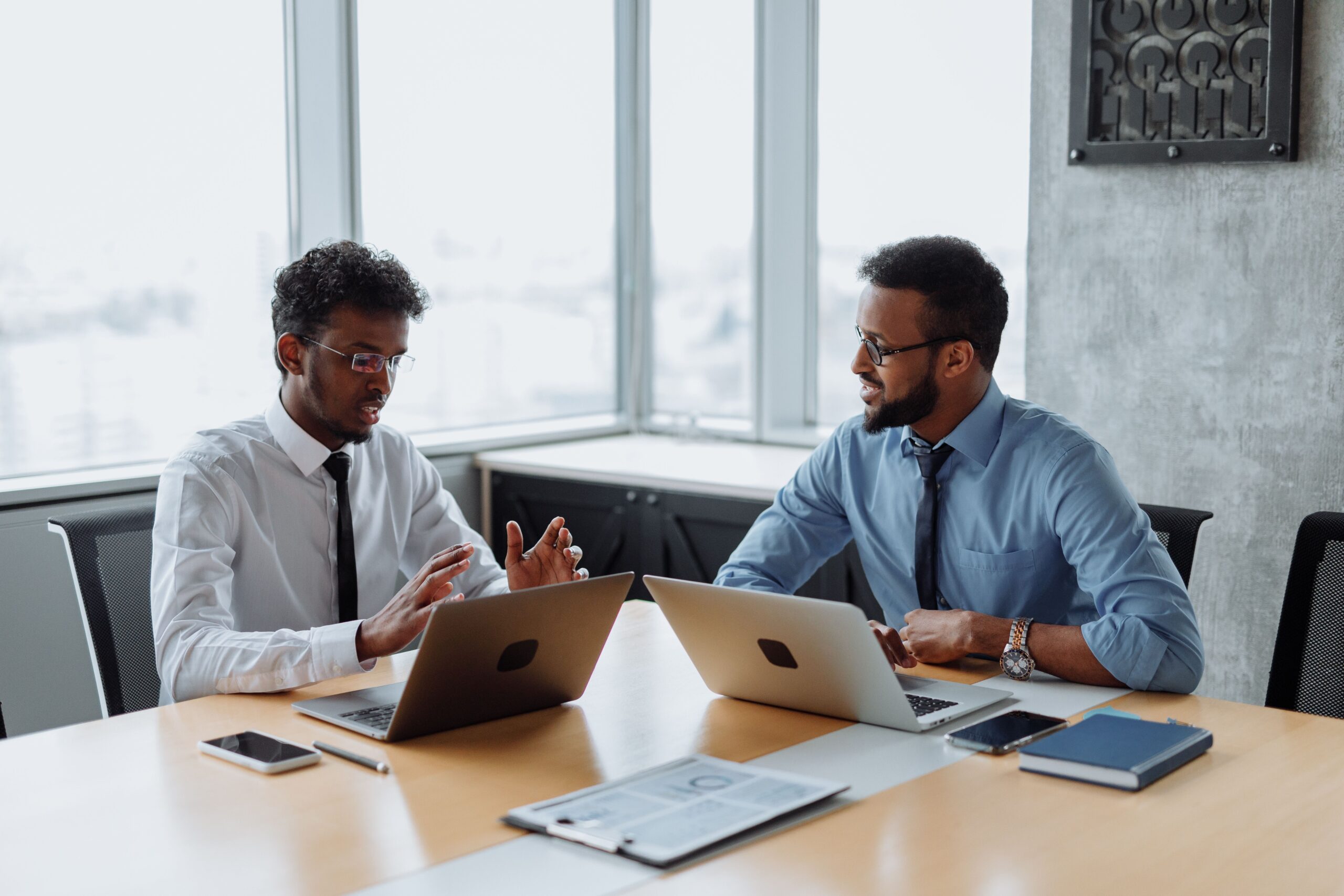 Two colleagues discussing which AI tool fits a specific business task on a laptop